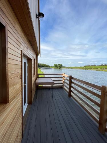 a wooden deck with a bench on the side of a lake at East Learmouth Lakeside Lodges - Larch Lodge in Cornhill-on-tweed