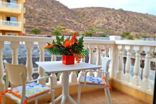 una mesa con un jarrón de flores en el balcón en Tropical Apartment - Heated Pool, en Palm-mar