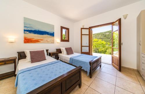 a bedroom with two beds and a balcony at Lemonia Beach Villa in Stavros