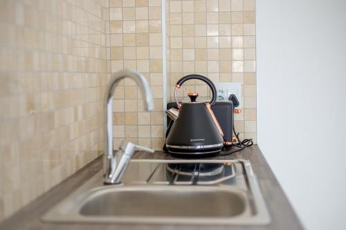 a tea kettle sitting on top of a kitchen sink at Urban Oasis Apartments at Hidas in Windhoek
