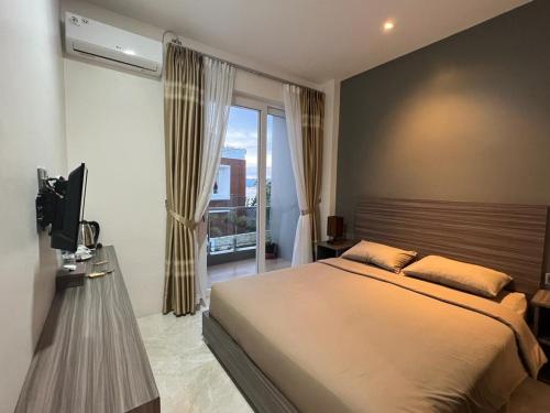 a bedroom with a large bed and a window at PURNAMA BALIGE HOTEL in Balige