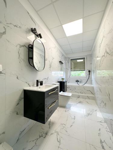 a white bathroom with a sink and a mirror at MILIA wine & event resort in Dunajský Klátov