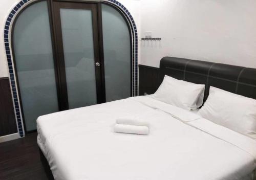 uma cama branca com uma cabeceira preta e almofadas brancas em RV @ U GARDEN STAY em Skudai