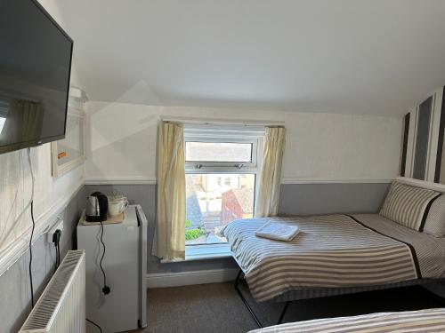 a small room with a bed and a window at Tuxford House in Blackpool