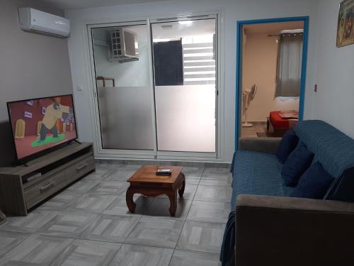 a living room with a couch and a tv and a table at F2 privé Rénové Green corner in Saint-Denis
