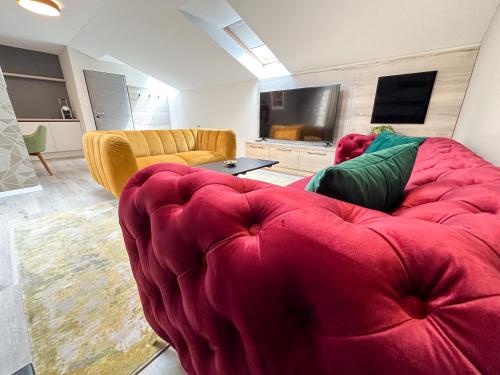a living room with a red couch and a tv at MILIA wine & event resort in Dunajský Klátov