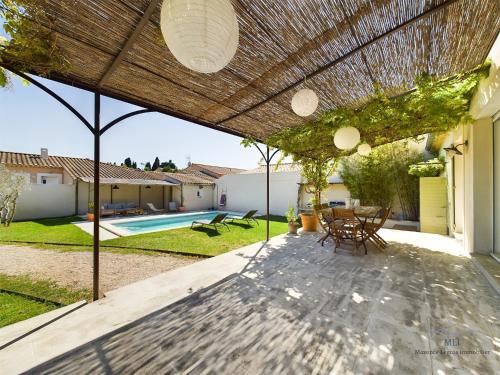 un patio avec une table et des chaises sous une pergola dans l'établissement Villa Calisse, 6 personnes à Maillane, à Maillane