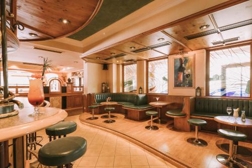 a restaurant with green seats and tables and windows at Hotel Montana in Obertauern