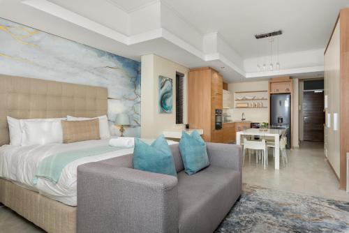 a bedroom with a bed and a couch and a kitchen at Crystal Towers 212 in Cape Town