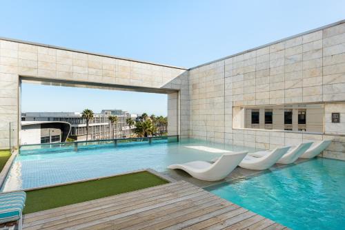 a swimming pool with white chairs on a building at Crystal Towers 212 in Cape Town