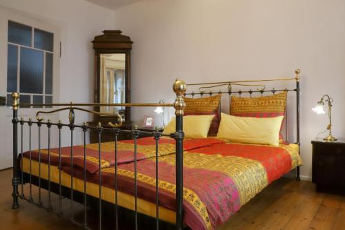 a bedroom with a black bed with a red and yellow blanket at Ferienwohnung im Sternenhof in Großkarlbach