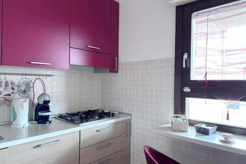 a kitchen with purple cabinets and a stove and a window at Appartamento Oasi di Pontenuovo in Sermoneta