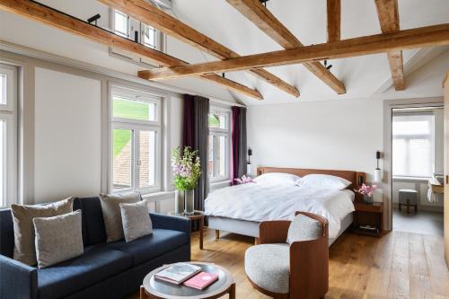1 dormitorio con 1 cama y 1 sofá azul en Appenzeller Huus Löwen en Gonten