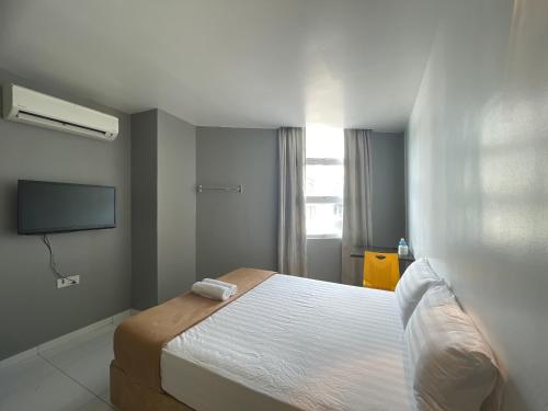 um quarto com uma cama e uma televisão de ecrã plano em Hotel Lavender Inn em Malaca