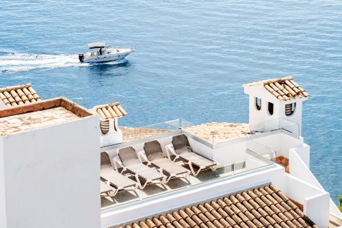 a boat in the water with chairs on a house at Hotel ROC Illetas & SPA in Illetas