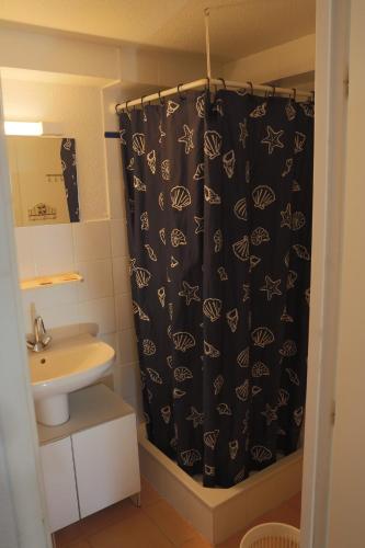 La salle de bains est pourvue d'un rideau de douche noir et d'un lavabo. dans l'établissement Nr 24 Vakantiehuisje Portiragnes Les Marines, à Portiragnes
