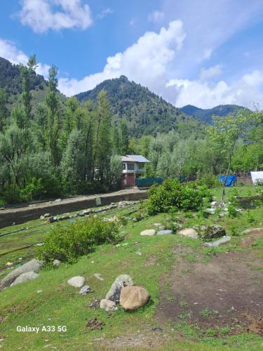 a house in a field with a mountain in the background at Al-Ayaan Guest House in Pahalgām