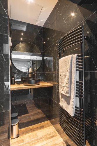 a black bathroom with a shower and a sink at Villa MaRisKa et son Spa, avec balcon in Ouistreham