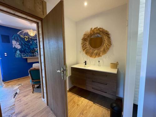 een badkamer met een wastafel en een spiegel aan de muur bij La Gallerie du Domaine des lupins in Xonrupt-Longemer