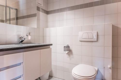 a white bathroom with a toilet and a sink at Apartment Hori - GRIWA RENT AG in Grindelwald