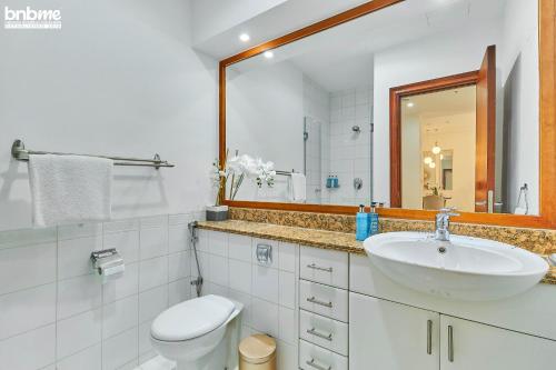 a bathroom with a sink and a toilet and a mirror at bnbmehomes - Marvellous Marina Gem nr Ain Dubai - G05 in Dubai