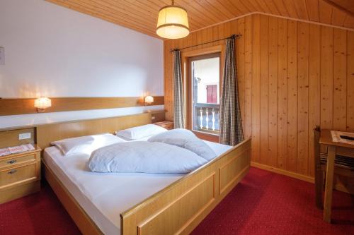 a bedroom with a large white bed with a window at Gasthof Löwen in Nova Levante