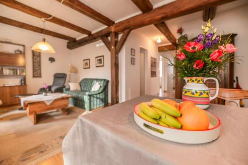 a bowl of fruit on a table with a vase of flowers at Ferienwohnung Johns in Bad Bevensen