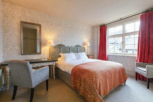 a bedroom with a bed and a desk and a mirror at The White Swan Inn in Pickering