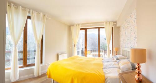 a bedroom with a yellow bed and large windows at Predela 2 Aparthotel in Bansko
