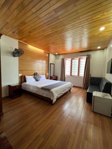 a bedroom with a bed and a couch and wooden ceilings at Thanh Bình Hotel in Ðoan Xá