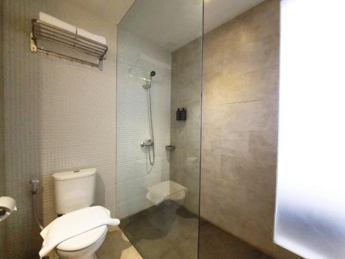 a bathroom with a toilet and a glass shower at Front One Gosyen Hotel Salatiga in Salatiga