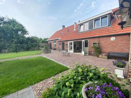 a brick house with a garden in front of it at Authentieke familieboerderij met sauna, tot 10 personen in Reutum