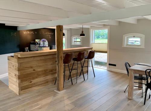 a kitchen with a counter with stools around it at Authentieke familieboerderij met sauna, tot 10 personen in Reutum