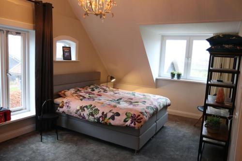 a bedroom with a bed and two windows at Authentieke familieboerderij, tot 10 personen in Reutum