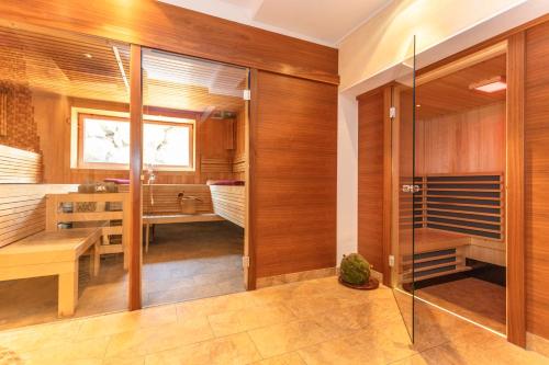 a bathroom with wooden walls and a glass door at Apart Hotel Alpenhof Werfenweng in Werfenweng