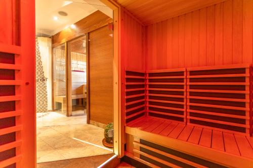 a sauna with red wood paneling and a red wall at Hotel Wenger Alpenhof in Werfenweng