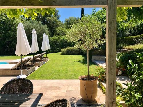 une terrasse avec deux parasols blancs et une piscine dans l'établissement Villa Milefleure, à Grimaud