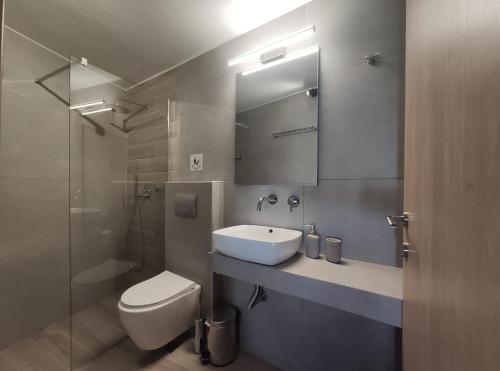 łazienka z umywalką, toaletą i lustrem w obiekcie Para Thin Alos Inn w mieście Neos Marmaras
