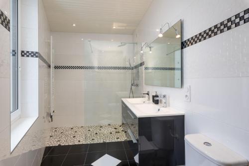La salle de bains blanche est pourvue d'un lavabo et d'une douche. dans l'établissement La Villa Sassolini, à Lyon