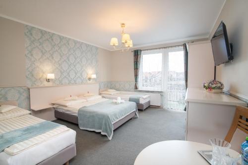a hotel room with two beds and a tv at Villa Mare in Łeba