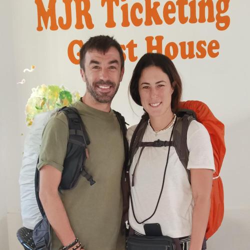 a man and a woman standing in front of a poster for a movie at MJR Ticketing Guest House in Ruteng