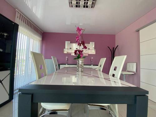 a dining room with a glass table and white chairs at Chez Florence Ammerschwihr in Ammerschwihr