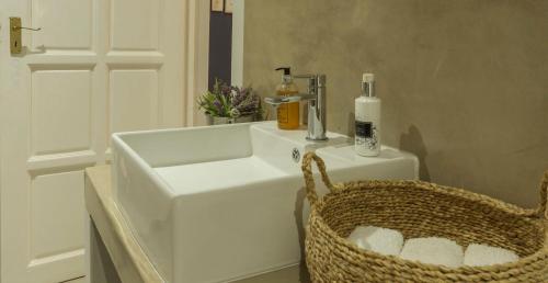 a bathroom with a white sink and a basket at Kingfisher Creek Cottage in Hoedspruit