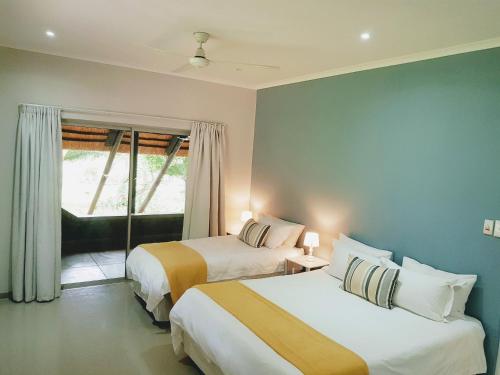 2 camas en una habitación de hotel con ventana en Kingfisher Creek Cottage, en Hoedspruit