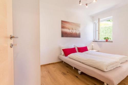 a bedroom with white walls and a bed with red pillows at Goldenhof Penon in Penone