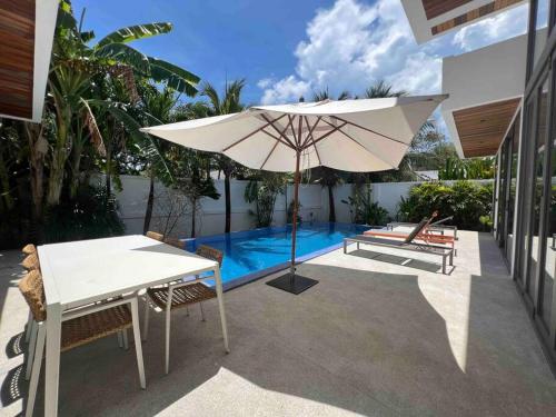 een patio met een tafel, een parasol en een zwembad bij Landmark Villa 2 in Ban Saiyuan (1)