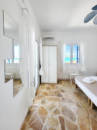 a white room with a stone floor and a table at SempreViva Sea Houses in Dhiakofti