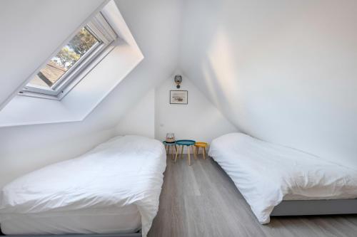 two beds in a attic bedroom with white walls at Appartement vue mer et les pieds dans l'eau! in Saint-Sébastien