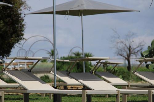 a row of picnic tables with an umbrella at Masseria del Carboj in Menfi
