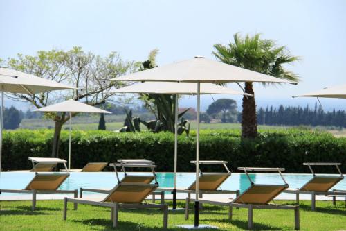 eine Gruppe von Stühlen und Sonnenschirmen neben einem Pool in der Unterkunft Masseria del Carboj in Menfi